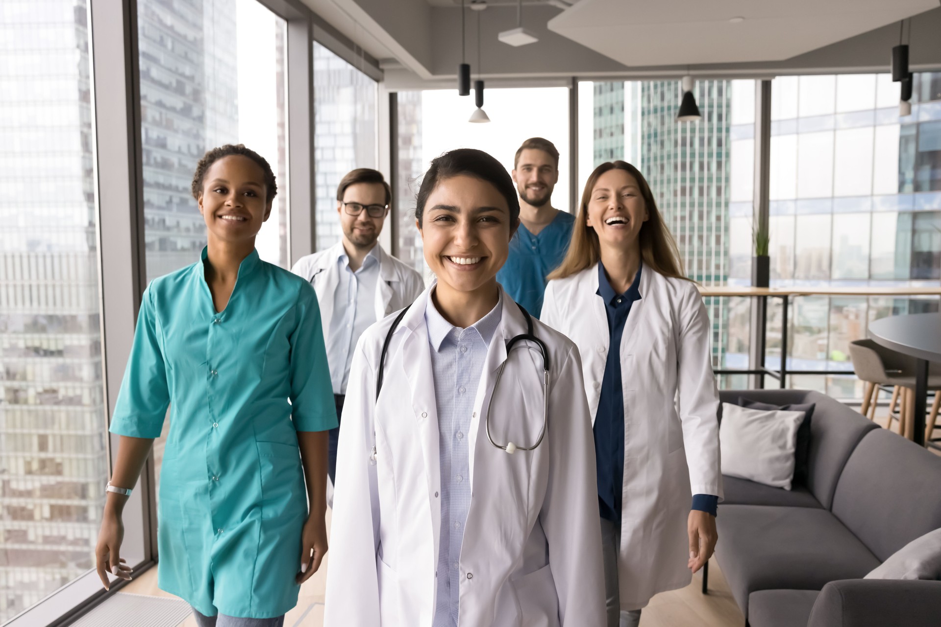 Portrait successful multiethnic young doctors group walking by modern clinic