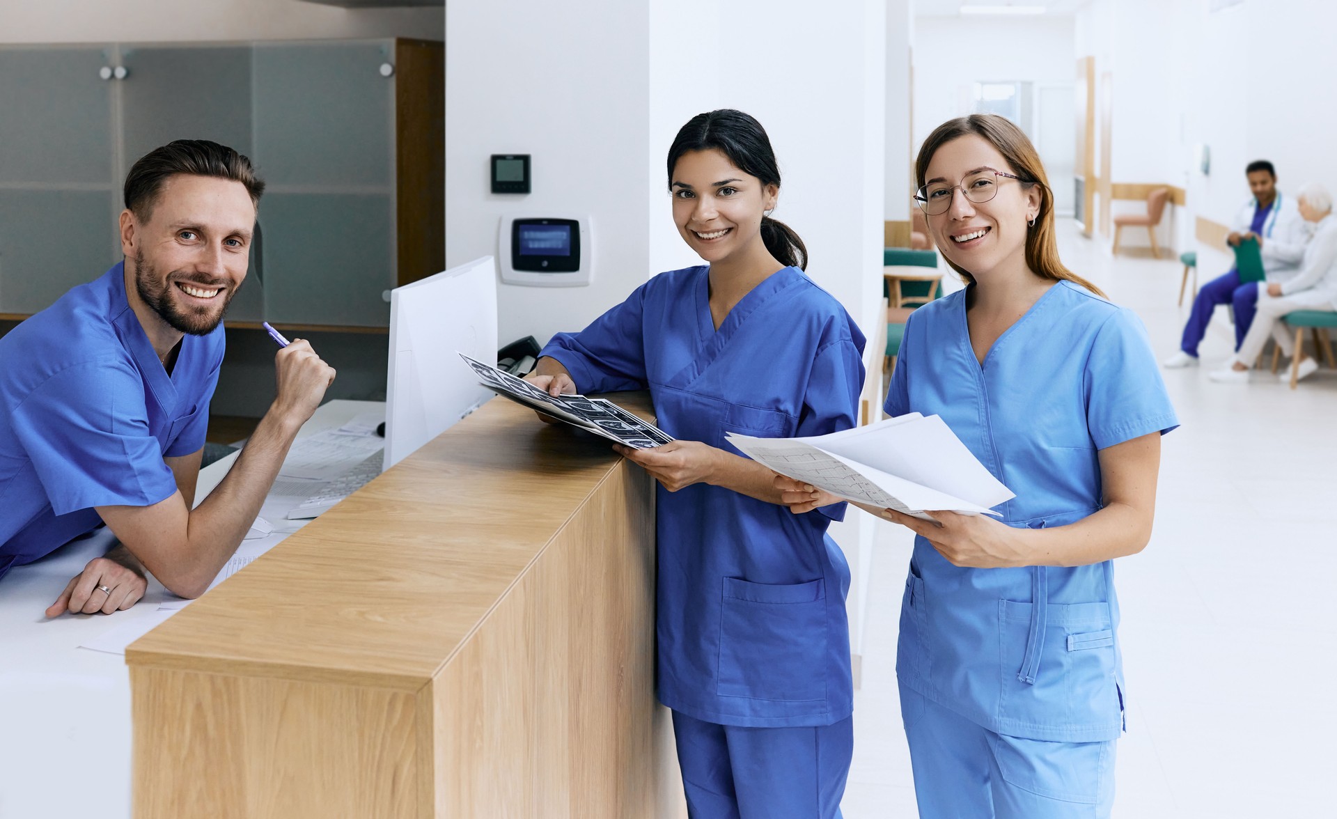 Nurse on duty talking with medical assistants during working day in medical clinic standing near reception desk at hospital lobby. Medical staff of clinic